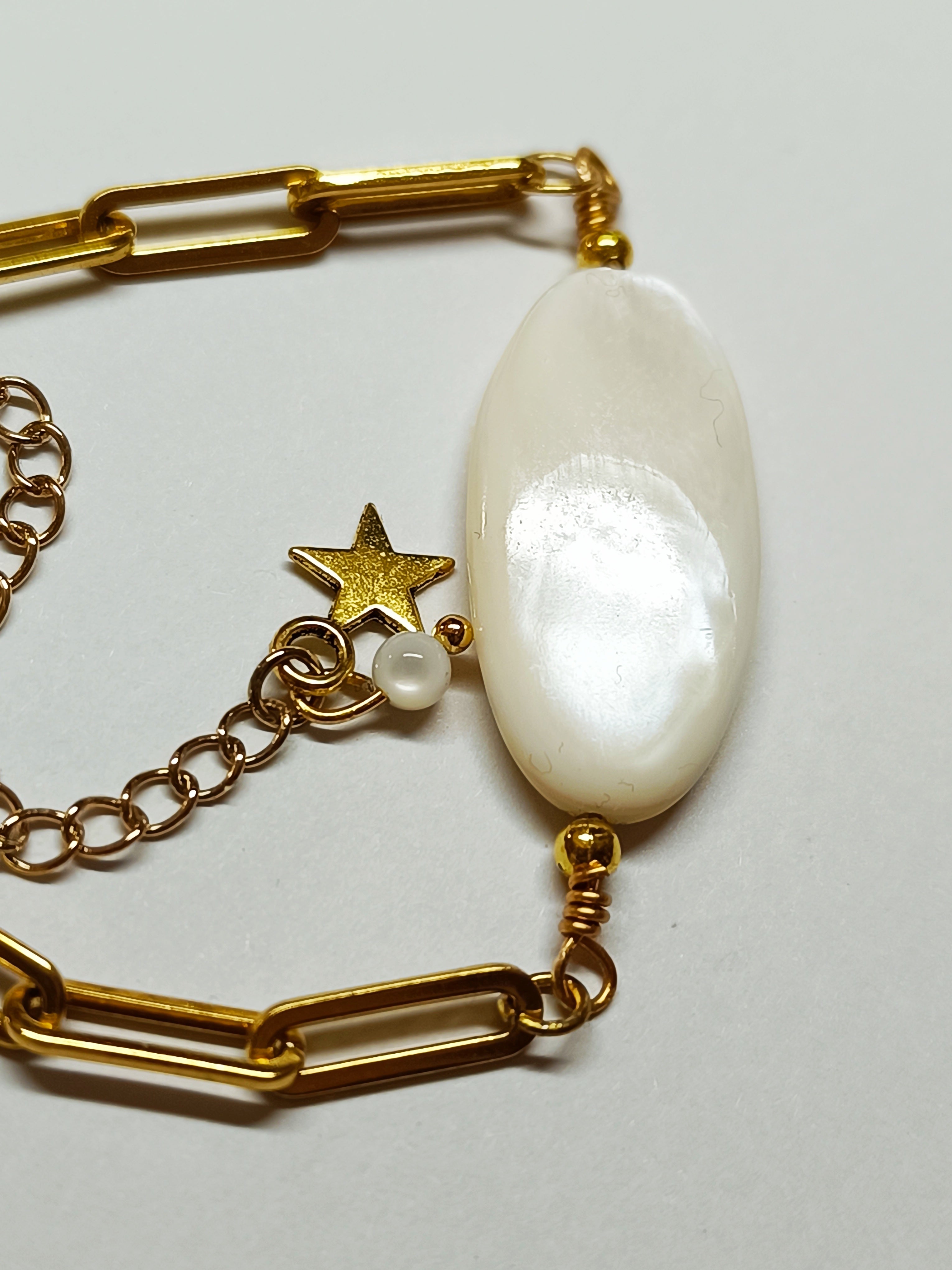 Vue rapprochée de la perle de nacre ovale et du pendentif étoile dorée du Bracelet AVA, mettant en évidence les finitions.