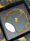 Bracelet AVA en nacre naturelle et chaîne dorée, avec pendentif étoile, présenté dans un élégant écrin noir