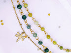 Gros plan sur les perles d'Agate Mousse vertes et bleues et la chaîne dorée du bracelet double SANACA, avec un charm libellule visible.
