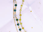 Détail rapproché du pendentif libellule doré et des perles d'Agate Mousse du bracelet double SANACA, montrant la finesse du bijou.