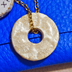 Gros plan sur un pendentif anneau artisanal "Le Murmure" scellé sous résine, révélant une spirale d'or incrustée à la feuille d'or, bijou d'intuition fait main dans le sud-ouest.