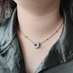 Gros plan sur le collier totem "L'Enfant Intérieur" porté, mettant en lumière l'impression délicate du mantra "Je veille sur toi" scellée sous la résine brillante.