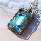Gros plan du pendentif "Aura" en labradorite bleue irisée, orné de fil de laiton et perles argent 925, fait main en wire wrapping.