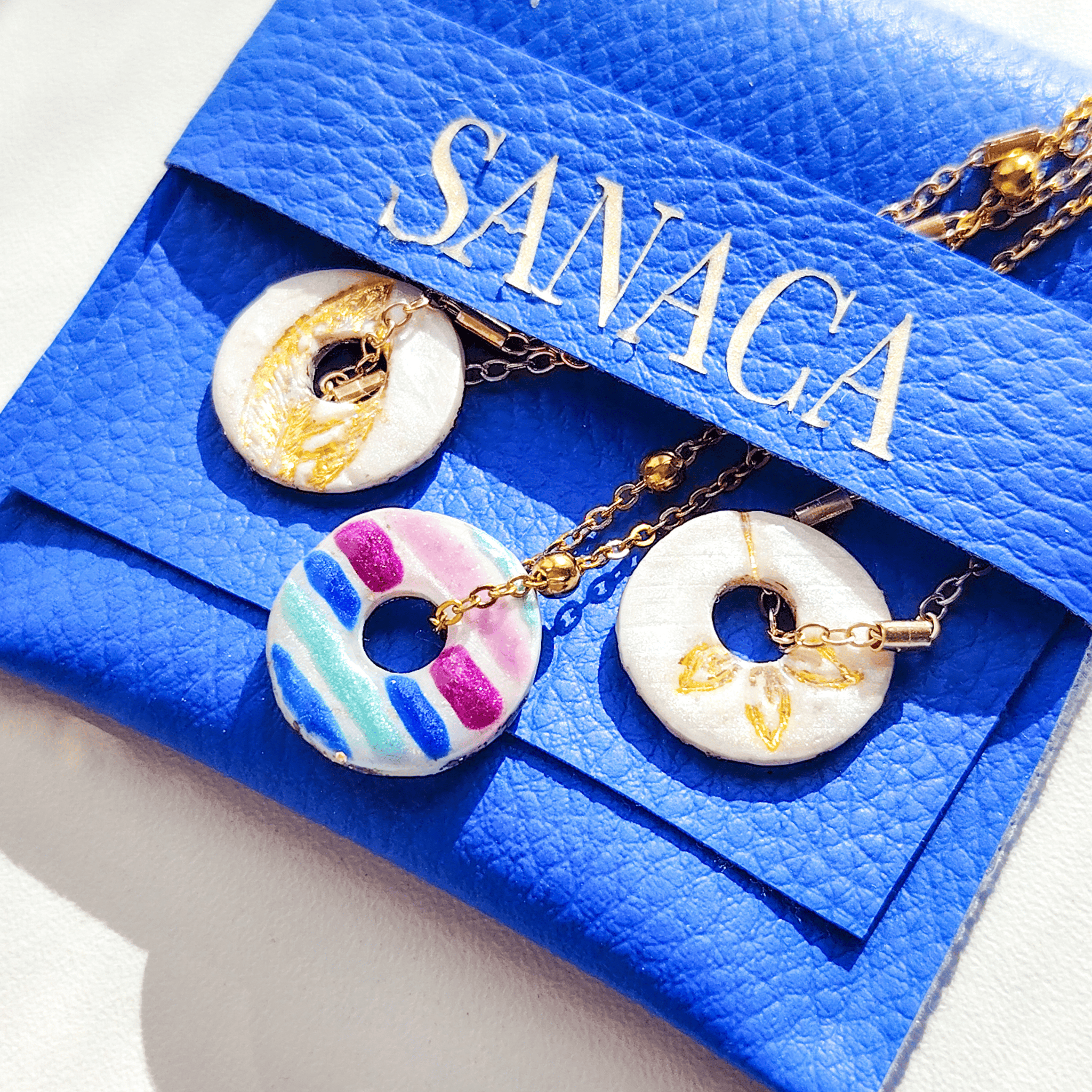 Présentation du bijou artisanal L'Équilibre dans son pochon bleu Sanaca, idéal pour un cadeau symbolique.