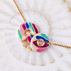 Composition de deux talismans colorés entrelacés avec une chaîne ornée de perles de culture pour un look bohème chic.