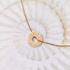 Gros plan sur un pendentif anneau artisanal "Le Murmure" scellé sous résine, révélant une spirale d'or incrustée à la feuille d'or, bijou d'intuition fait main dans le sud-ouest.