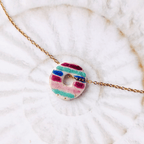 Pendentif Le Cap Sanaca avec ses lignes vibrantes bleues et violettes, centré sur une chaîne fine en acier inoxydable