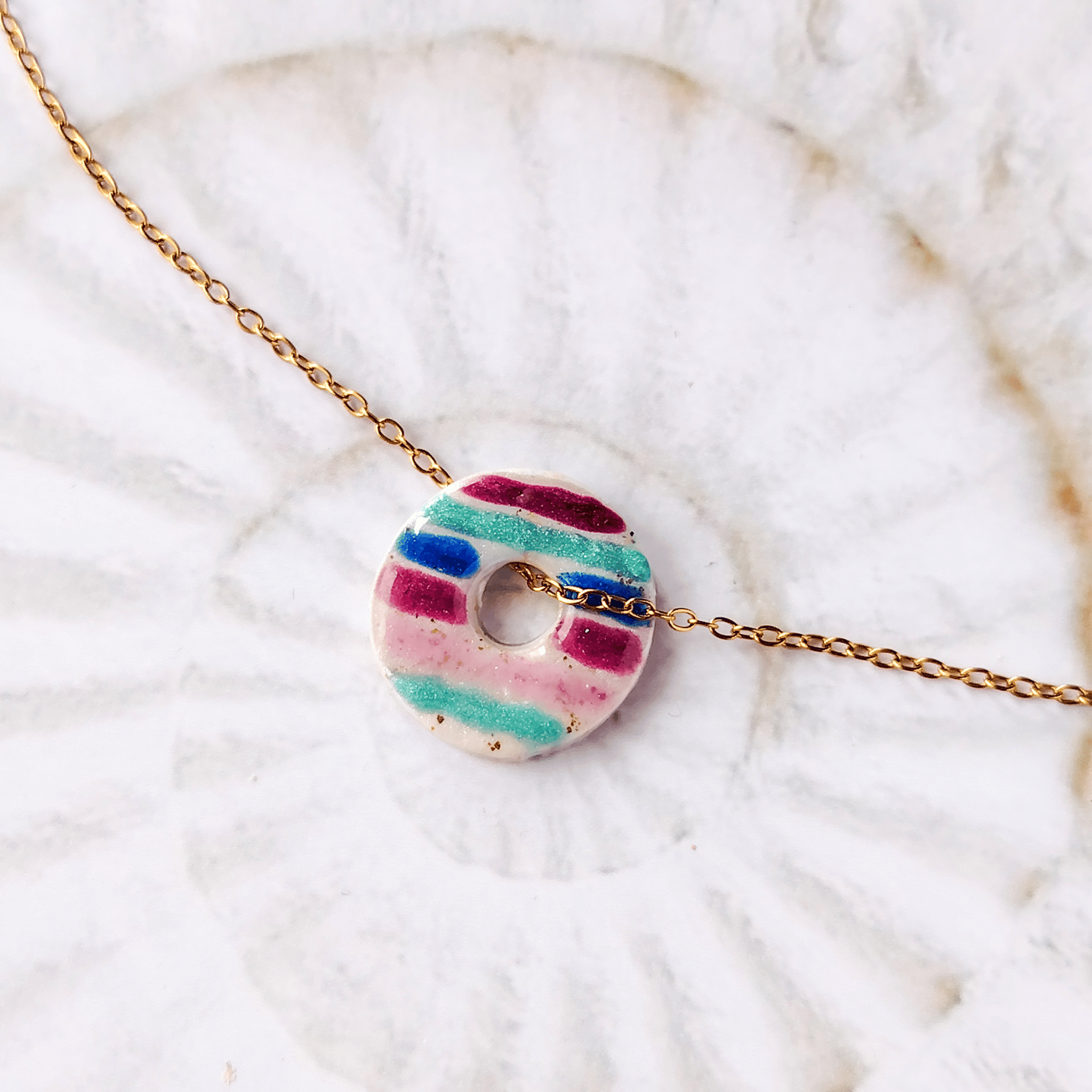 Pendentif Le Cap Sanaca avec ses lignes vibrantes bleues et violettes, centré sur une chaîne fine en acier inoxydable