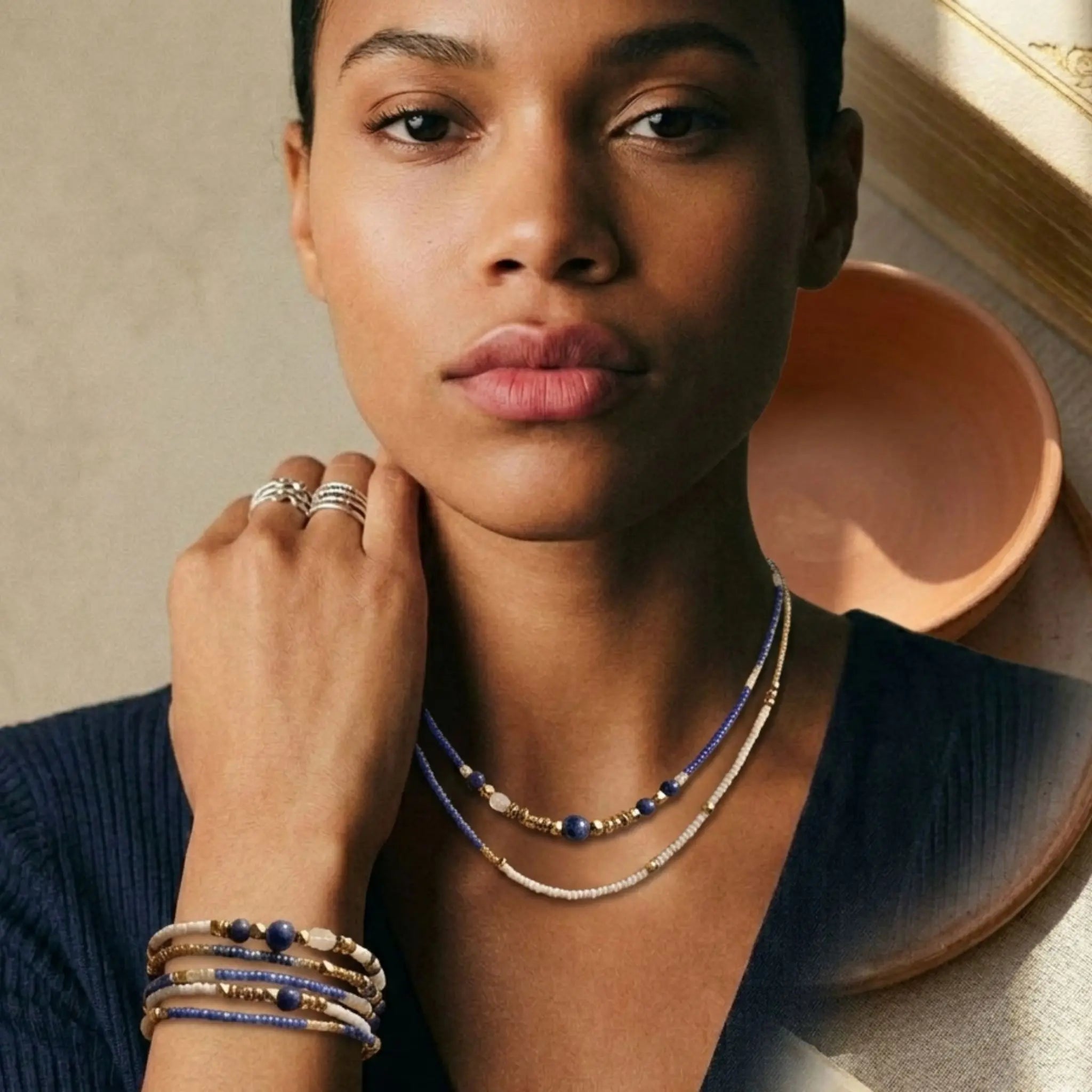 Mannequin portant le collier Marie en version sautoir long autour du cou et le bracelet assorti en multi-tours au poignet, illustrant la polyvalence du bijou en Lapis-Lazuli et doré.