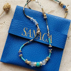 Collier 2-en-1 Sanaca en jaspe bleu présenté sur sa pochette signature en cuir bleu et marquage or.