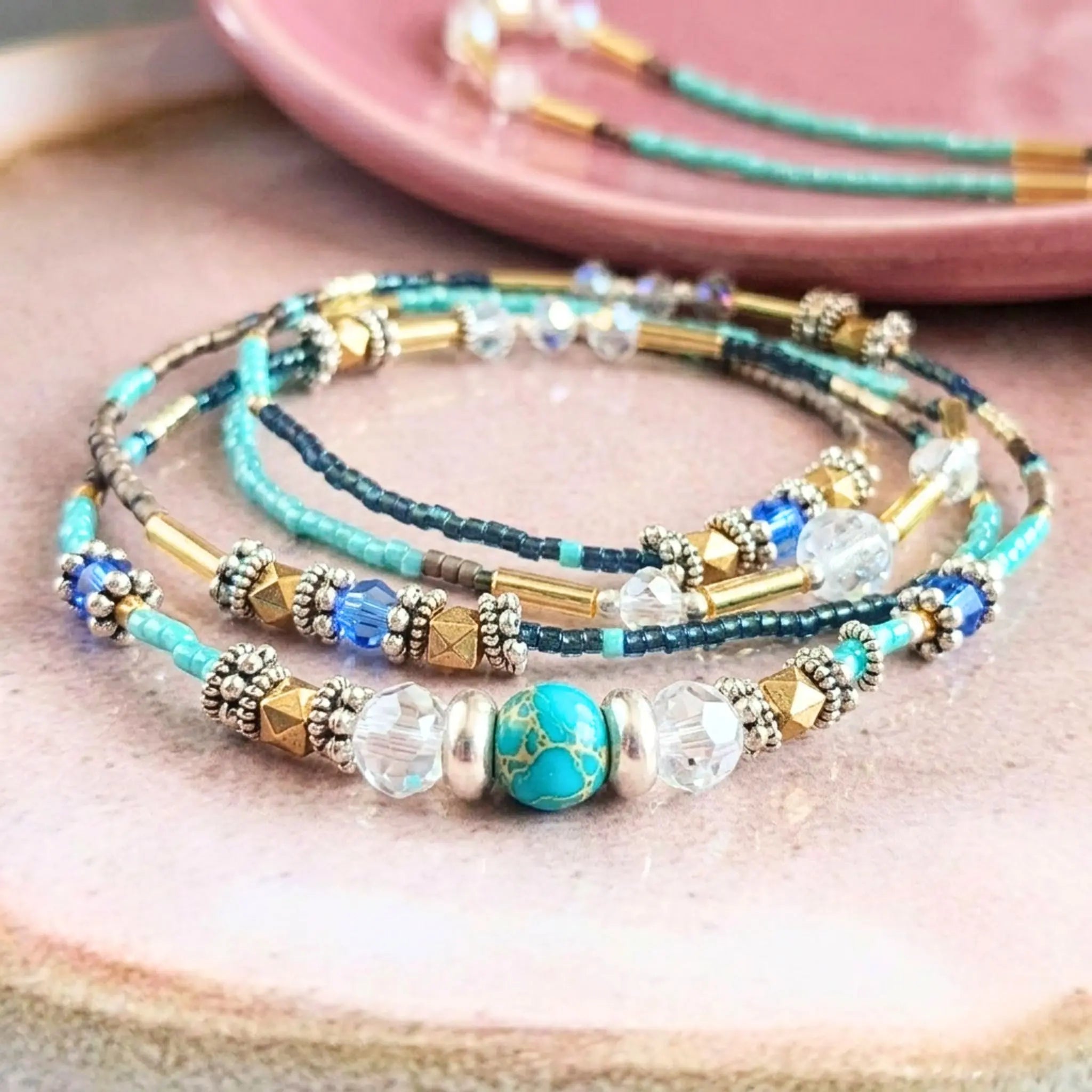 Gros plan sur le bijou modulable Luz enroulé, mettant en avant les détails de la pierre jaspe turquoise de 6mm, les cristaux de Bohème et les finitions dorées.