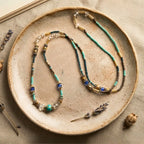 Collier 2-en-1 Luz exposé sur une assiette en céramique artisanale avec brins de lavande, photographie éditoriale de bijou en pierres naturelles turquoise et or.