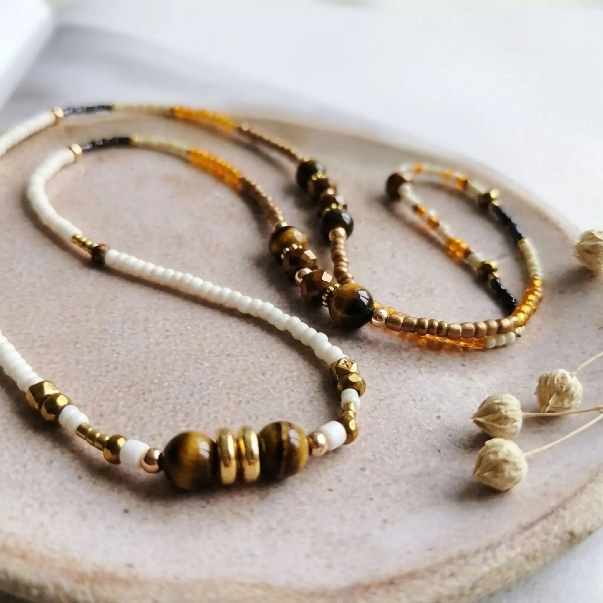 Détail macro du collier Ambre Sanaca, perles en pierre naturelle œil-de-tigre, perles de verre blanches et ambrées, style bohème chic.