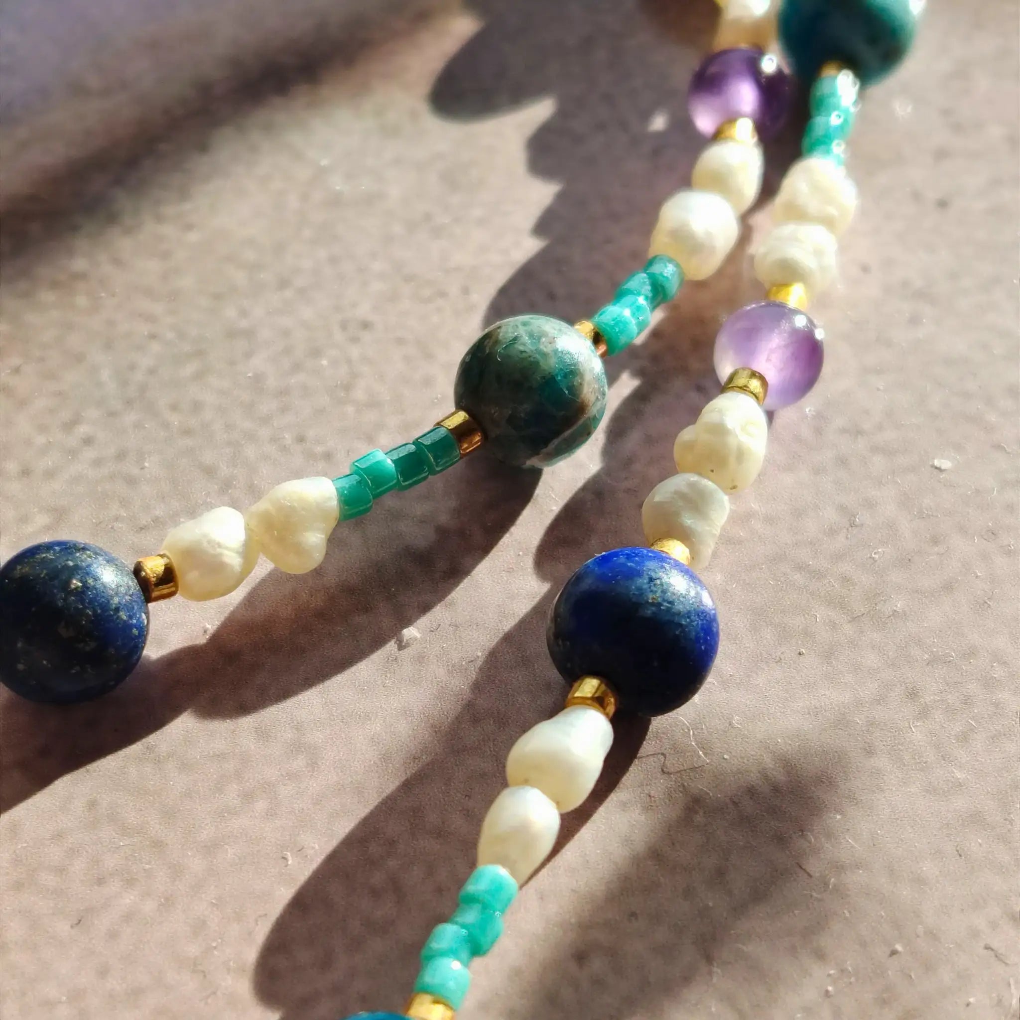 Détail du collier Biarritz montrant les perles d'eau douce baroques, l'apatite bleue, le lapis-lazuli et l'améthyste avec finitions dorées