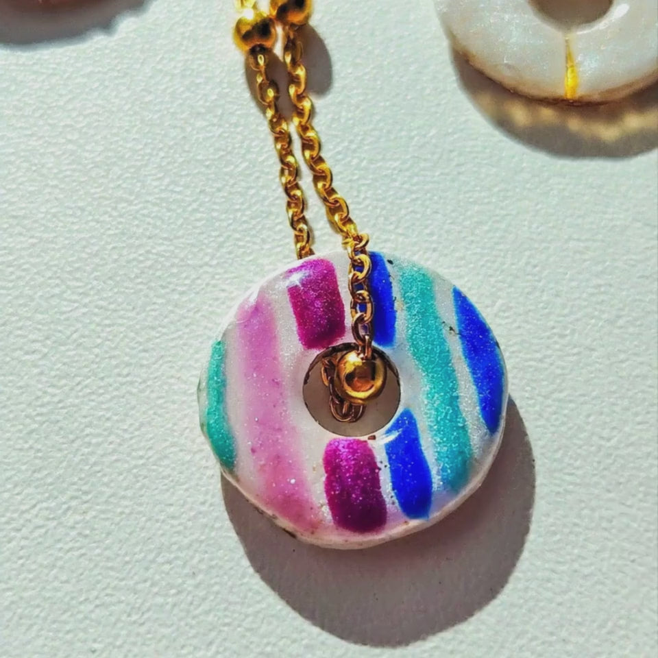 Vidéo gros plan d'un talisman Sanaca aux lignes colorées et irisées, manipulé à la main pour montrer sa texture lisse et ses reflets de mica